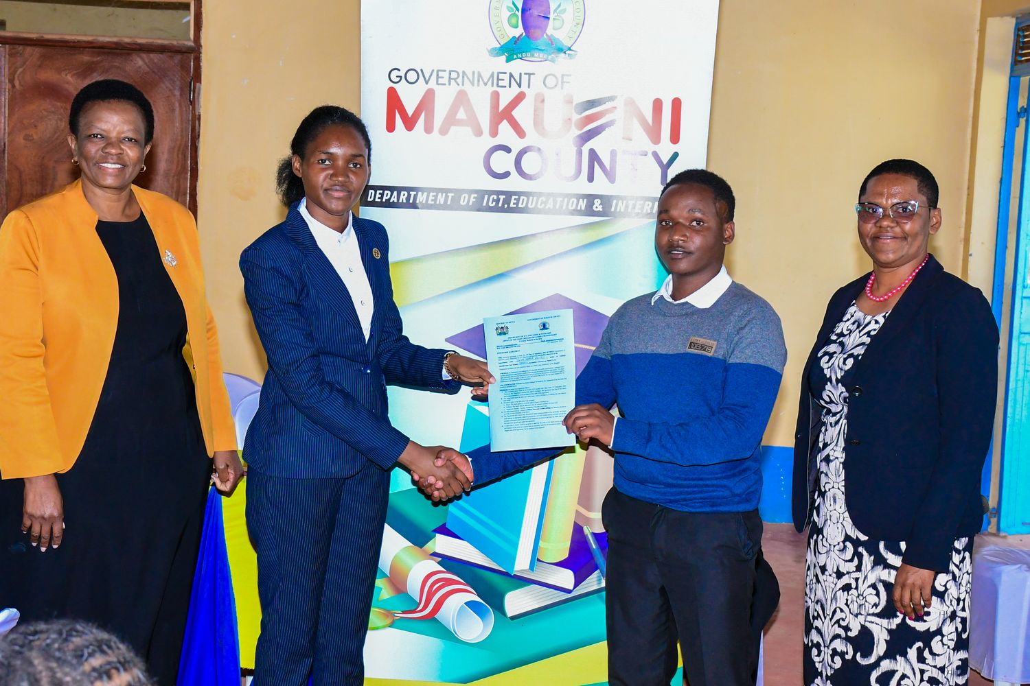 Intern receiving an internship agreement from Makueni County officials